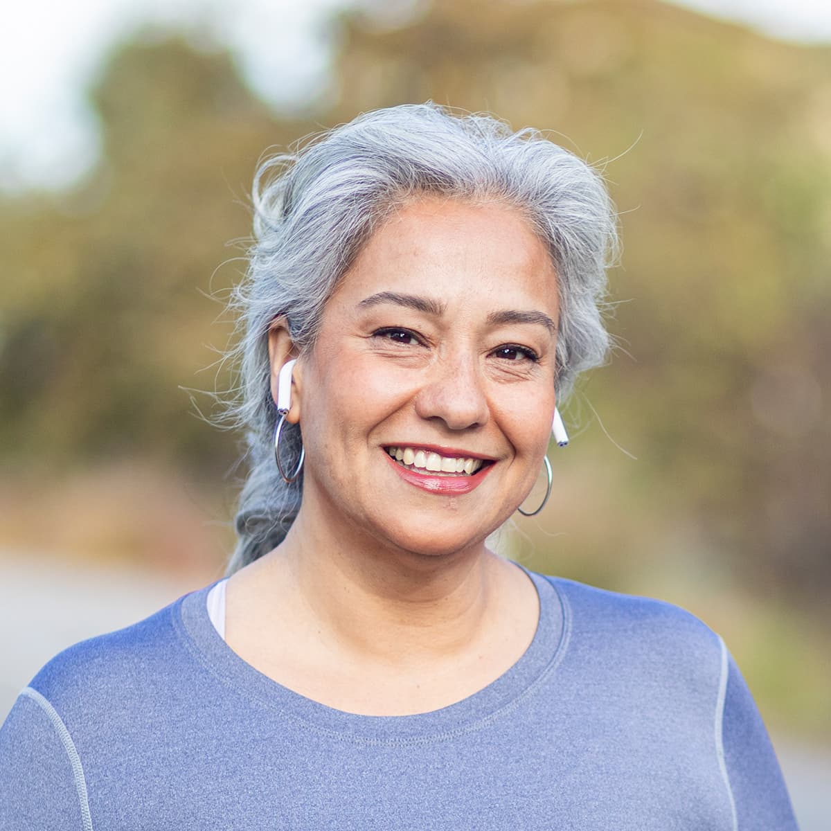 Woman with silver hair smiling while wearing airpods