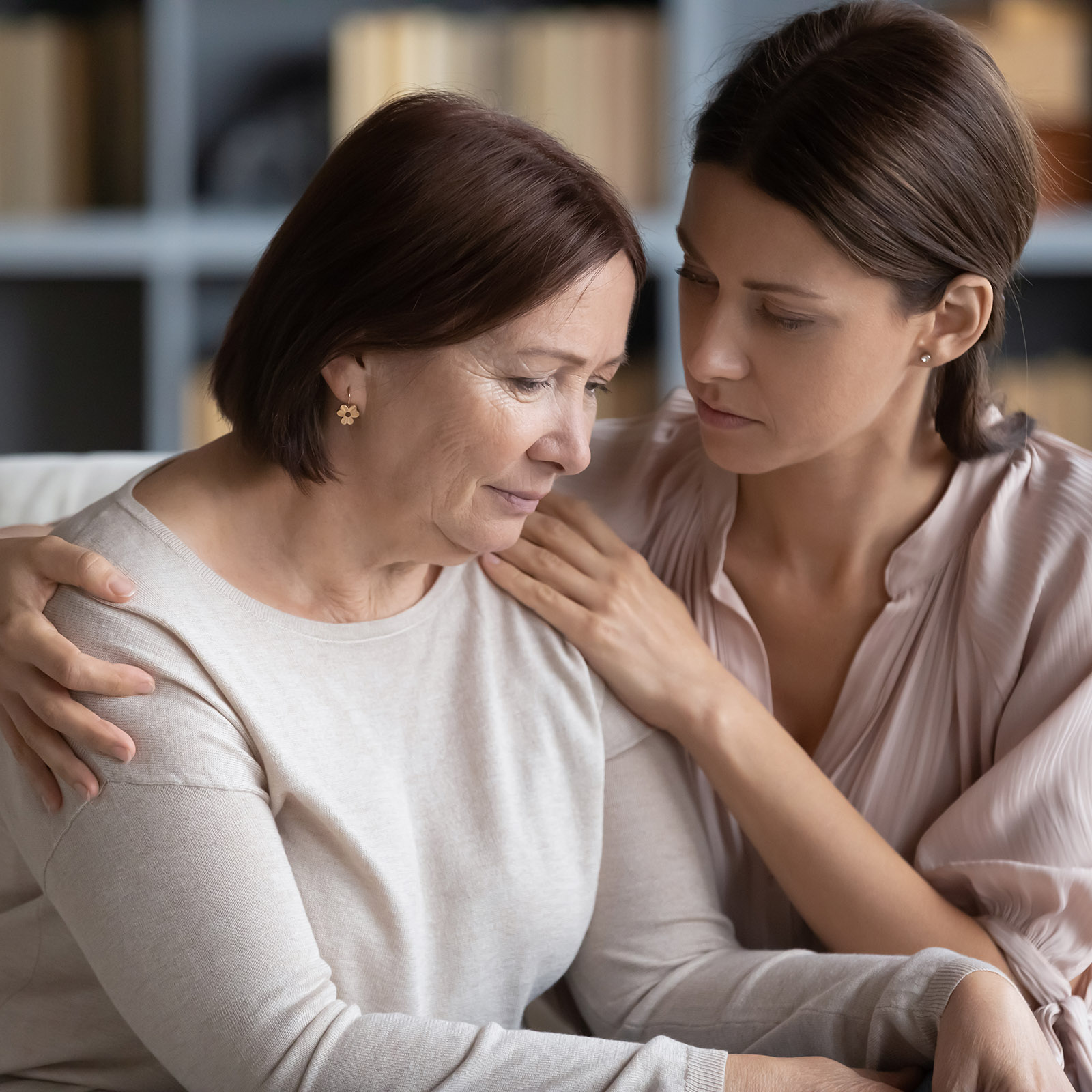 Compassionate woman embracing shoulder of unhappy stressed middle aged mommy.
